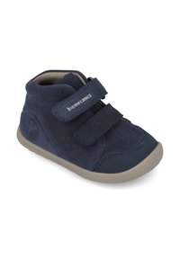 Scarpa alta in suede blu navy con due cinturini in velcro, suola in gomma, punta arrotondata e sottili accenti di logo sul lato e sul cinturino.
