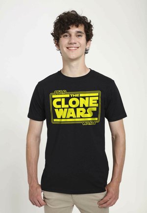 Černé bavlněné tričko s velkým žlutým logem "Star Wars: The Clone Wars" vytištěným tučným písmem na přední straně. Krátké rukávy a kulatý výstřih.