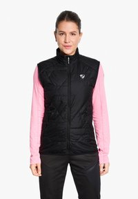 Black insulated vest with diamond-shaped quilting, high collar, full zipper, side pockets, and a logo on the chest. Worn over a pink long-sleeve shirt.