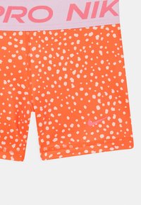 Nike Pro Shorts in leuchtendem Orange mit verstreuten weißen Punkten. Mit einem pinken elastischen Bund, auf dem "PRO NIKE" steht, und einem kleinen pinken Logo.