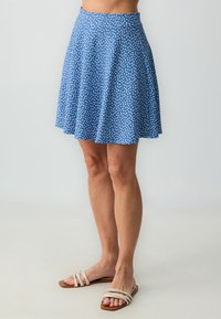 Blauwe rok met witte stippen, uitlopende ontwerp, gestructureerde stof en brede tailleband. Gecombineerd met platte, strap-sandalen.