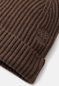 Brązowa dzianinowa czapka z prążkowanym wzorem. Posiada podwinięty mankiet oraz małe wytłoczone logo z boku. Miękki materiał i ciepły design.