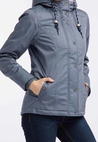 Veste à capuche grise avec une texture lisse, fermeture à boutons et deux poches frontales. Dispose de cordons de serrage avec des accents en bois.