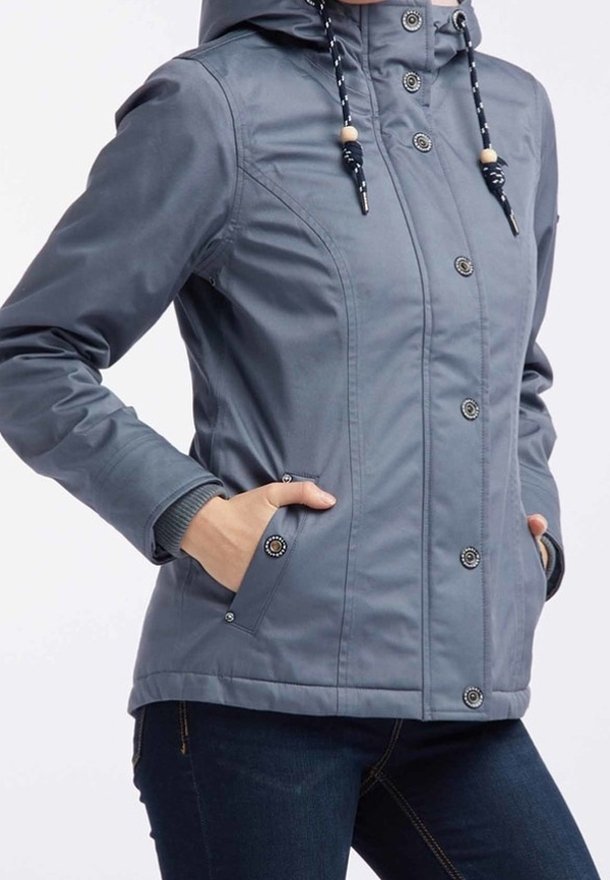 Veste à capuche grise avec une texture lisse, fermeture à boutons et deux poches frontales. Dispose de cordons de serrage avec des accents en bois.