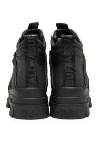 Zwarte chunky platform sneakers met dikke zolen, gevoerde kraagjes en "Buffalo"-branding op hielstukken en zolen, gezien van achteren.