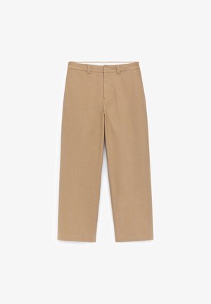 Pantalon beige à jambes larges avec une texture lisse, taille mi-haute, passants pour ceinture et deux poches avant. Détails de couture soignés et sans motifs.
