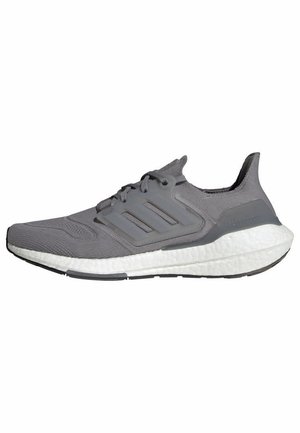 Chaussure de course grise Adidas avec dessus en mesh, trois bandes latérales, semelle intermédiaire blanche amortie et semelle extérieure noire sur fond blanc.