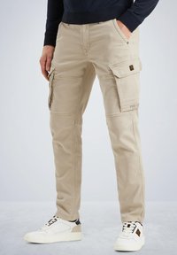 Beige cargo-bukser med flere sidelommer, lynlåslukninger og et lige ben-design. Stoffet virker let og holdbart.