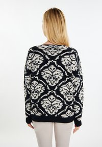 Pulover negru supradimensionat tricotat, cu un model floral alb, manșete și tiv bandat. Finisaj texturat, croială lejeră și decolteu larg.