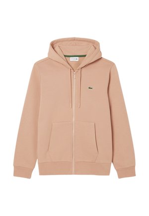 Haut à fermeture éclair rose clair en tissu doux, doté d'une poche kangourou, d'une capuche avec cordon de serrage réglable et d'un logo vert sur la poitrine.