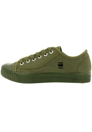 Niedriger Sneaker aus olivgrünem Canvas mit Gummisohle, Schnürsenkeln und kleinem schwarzem Logo an der Seite.
