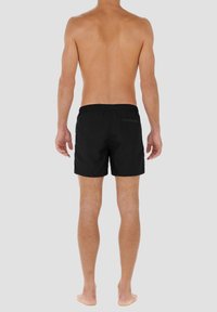 Shorts de bain noirs en tissu léger, dotés d'une taille élastique et d'une poche arrière, présentant un design simple et des lignes épurées.