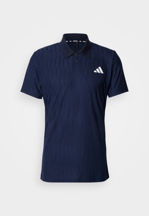 Tengerészkék póló texturált mintával, rövid ujjal és klasszikus gallérral. Bal mellrészen fehér logó díszítéssel.