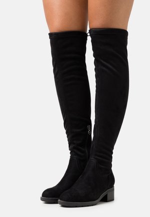 Black suede over-the-knee boots with a rounded toe, slouchy design, low block heel, and side zipper detail. Soft texture and seamless finish.