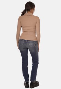 Maglione a maniche lunghe a coste color marrone chiaro con colletto, abbinato a jeans skinny in denim blu scuro e scarpe con plateau nere.