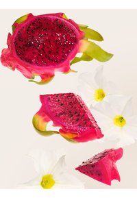 Fruit du dragon rose vif coupé en trois morceaux avec une peau à pointe verte, entouré de fleurs blanches aux centres jaunes sur un fond clair.