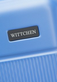 Blue textured fabric with horizontal and vertical patterns. Features a rectangular black label with "WITTCHEN" in silver letters.