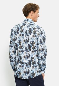 Lichte langekleurige blouse met een bloemenpatroon in blauw, zwart en wit, met een spread collar en knoopmanchetten.