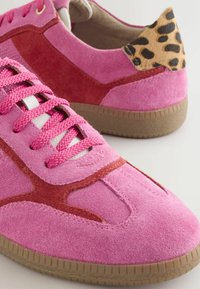 Rosa Wildlederschuhe mit kontrastierenden roten Akzenten, strukturiertem Leopardenmuster am Absatz und runder Zehenpartie. Verfügt über rosa Textil-Schnürsenkel und Gummi-Außensohle.