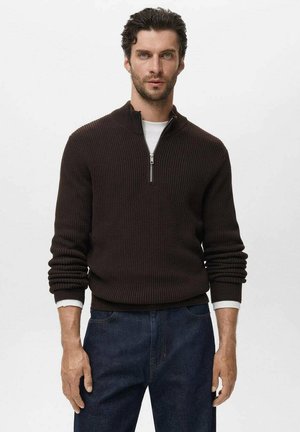 Brown ribbed half-zip sweater with long sleeves, featuring a white undershirt, paired with dark denim jeans. Simple, textured design.