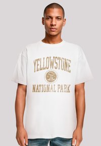 White cotton t-shirt featuring gold text reading "YELLOWSTONE NATIONAL PARK" and a graphic logo. Short sleeves, relaxed fit.