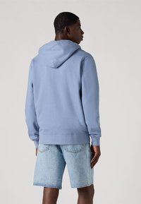 Lichtblauwe hoodie met een trekkoordcapuchon, kangoeroezak en ribgebreide mouwen, gecombineerd met lichtdenim shorts. Gladde katoenmix materiaal.