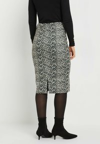 Leopardenmuster Bleistiftrock aus dehnbares Material, mit einem Schlitz hinten, getragen mit schwarzen Knöchelstiefeln und Strumpfhose.