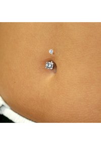 Anneau ombilical avec une pierre ronde et claire, sertie dans un métal argenté, avec une fermeture à épingle push-pin, positionnée dans une zone de nombril percée sur la peau.