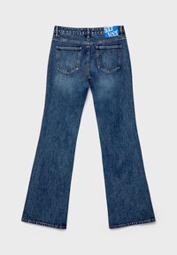 Jeans en denim évasés de couleur bleu foncé avec une finition texturée. Comprend une étiquette de ceinture bleue et deux poches arrière avec des bords façonnés.