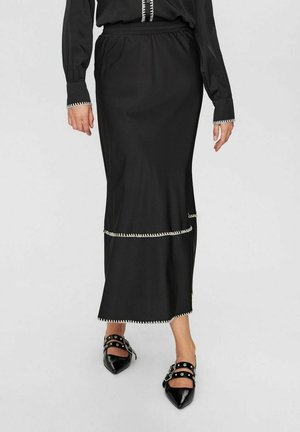 Svart, ankel-lång kjol med elastisk midja, och vit dekorativ stitching längs fållen och sömmarna. Slät, lättviktig tyg.