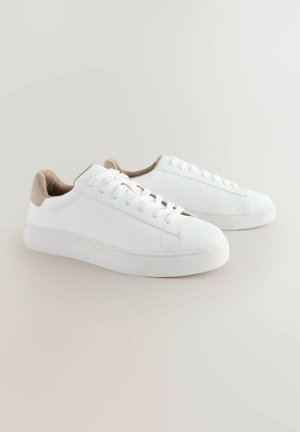 Białe trampki z teksturowanej tkaniny, okrągłym noskiem, płaską gumową podeszwą i beżowym akcentem na pięcie. Związane sznurowadłami z sześcioma oczkami.