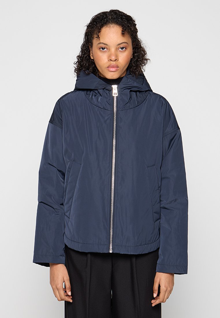 Marine pufferjack met capuchon, voorzien van een rits aan de voorkant, zijzakken en een gestructureerde stof. Ontspannen pasvorm met een gladde afwerking.