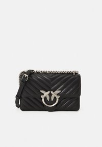 Svart quiltet skinnveske med tversoverstropp, chevronmønster, sølvfarget beslag og dobbel fuglemotiv på forsiden med en detaljert sirkulær ring.