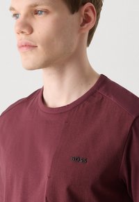 Marokas T-krekls ar ribotu tekstūru vienā pusē un gludu audumu otrā pusē, ar melnu "BOSS" logo uz krūškurvja.