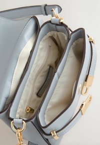 Világoskék bőrtáska arany színű csatokkal, nyitott rekeszekkel és bézs színű textil belső zsebel cipzárral.