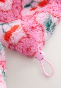 Rosa floralmusterter, flauschiger Stoff mit verstellbarer rosa Kordel und Knebelverschluss auf weißer Oberfläche.