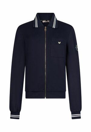 Veste zippée bleu marine avec col et poignets rayés, poche poitrine avec petit emblème et patch brodé sur la manche gauche.