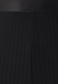 Czarna prążkowana tkanina z szerokim elastycznym paskiem w talii, z pionową teksturą i czystymi liniami na całej powierzchni. Odpowiednia do odzieży sportowej.