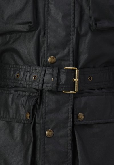 Veste noire en tissu lisse et résistant à l'eau. Elle comporte une ceinture, des accessoires en métal doré et deux poches avant avec des fermetures à pression.