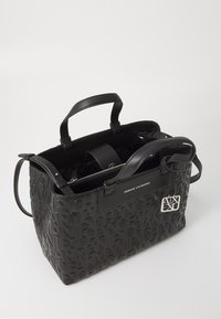 Svart håndveske med preget "Armani Exchange"-logo, har teksturert syntetisk materiale, doble håndtak og en dekorativ sølvlogo acccent.
