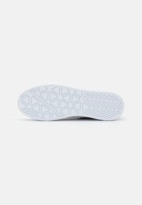 Semelle blanche de basket avec des motifs géométriques comprenant des lignes, des triangles et des cercles, affichée à plat sur un fond gris clair.