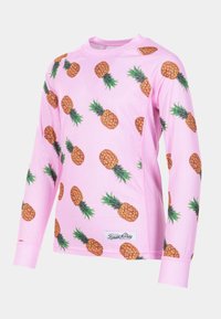 Camicia rosa a maniche lunghe con stampa ananas su tutta la superficie. Realizzata in tessuto rigato con scollo rotondo e maniche con polsini. Dettaglio con etichetta bianca.