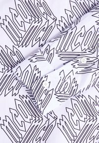 White shirt with long sleeves, featuring black bold geometric text pattern and white buttons on the cuff.