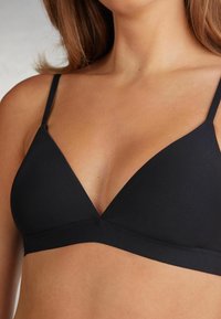 Svart triangelformad bh med tunna justerbara axelband, slät yta och ett brett underband för stöd. Minimalistisk design utan dekorationer.