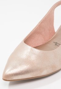 Chaussure plate pour femme métallisée rose clair à bout pointu, avec un talon découpé et une doublure intérieure douce.