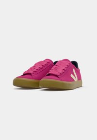 Pink sneakers made of textile with a smooth texture, featuring a white logo, round toe, and a gum sole for grip.