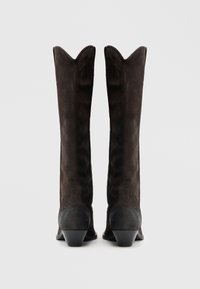 Térdig érő barna színű velúr csizma, hegyes orral és hullámos felső szegéllyel, blokksarokkal és sima textúrával az alapnál.
