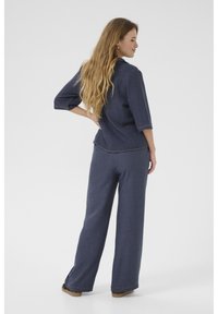 Top blu navy, dalla vestibilità ampia con maniche a tre quarti e leggera cucitura, abbinato a pantaloni a gamba larga nello stesso tessuto. Texture morbida.
