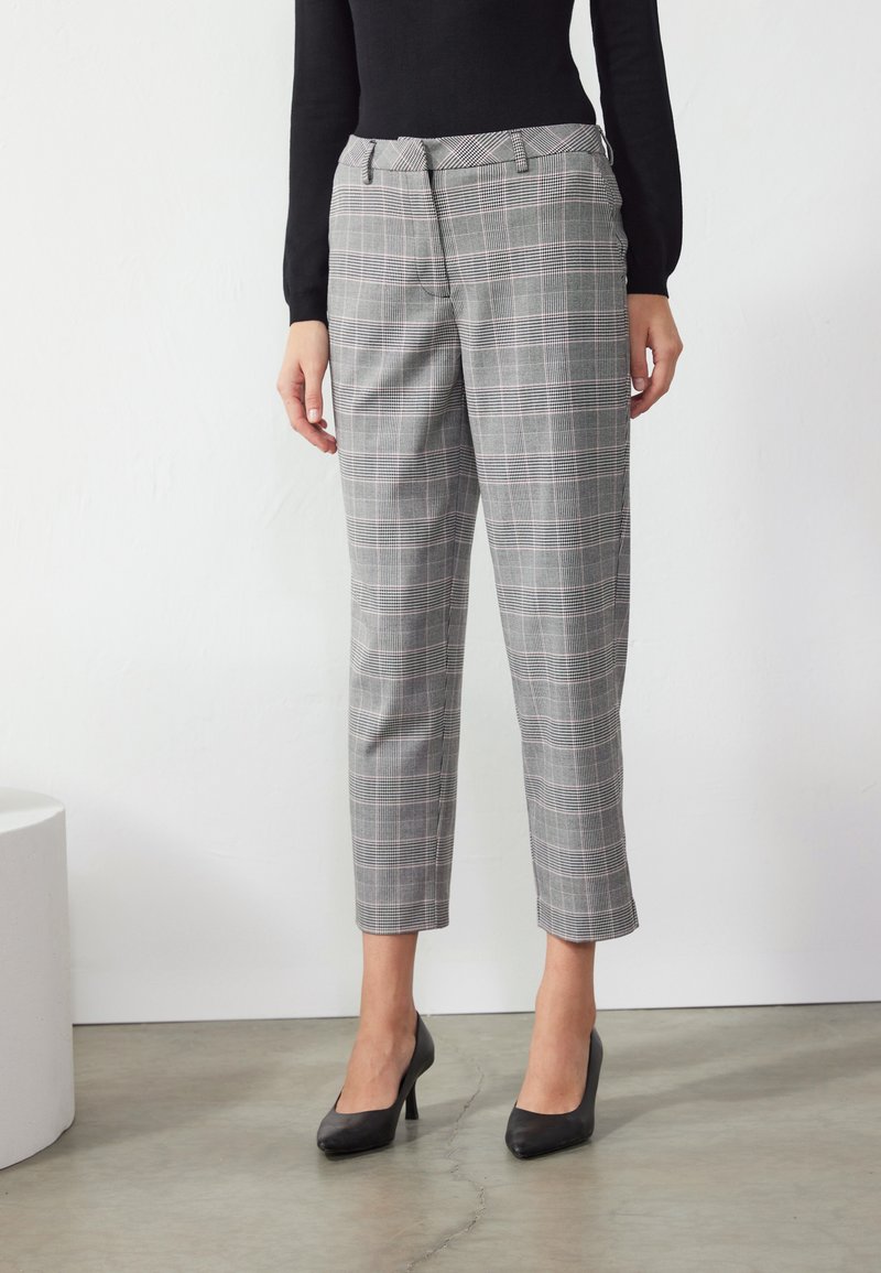 Pantalon gris à carreaux avec une coupe ajustée, présentant une taille mi-haute et un ourlet court. Le matériau a une texture lisse avec des lignes d'accent subtiles.