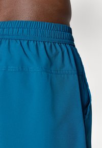 Türkise Sportshorts mit elastischem Bund, glatter Textur und Seitentaschen. Verfügt über dezente Nähte an den Seiten.